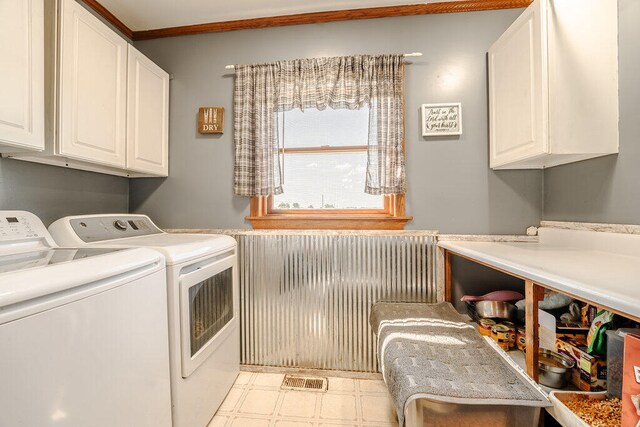 clothes washing area featuring light tile patterned floors, washing machine and clothes dryer, and cabinets