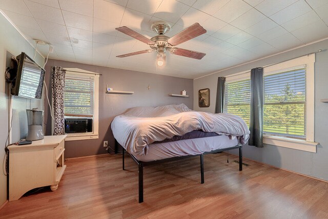 bedroom featuring ceiling fan, light hardwood / wood-style flooring, and cooling unit