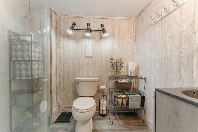 bathroom with hardwood / wood-style flooring, wood walls, walk in shower, and toilet