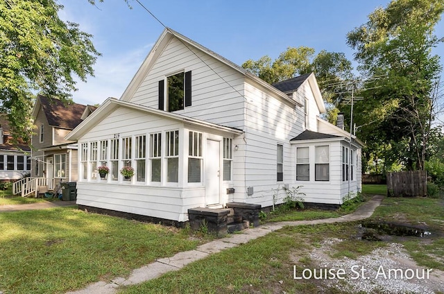 exterior space featuring a lawn, fence, and a sunroom