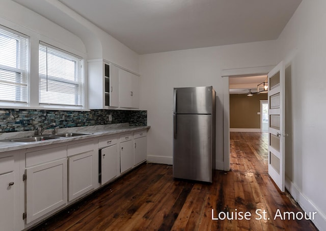 kitchen with stainless steel fridge, backsplash, dark wood-type flooring, sink, and white cabinets