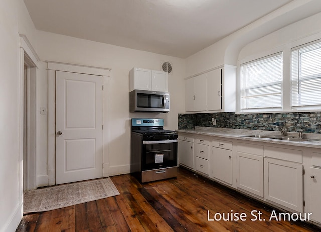 kitchen with backsplash, appliances with stainless steel finishes, white cabinetry, sink, and dark hardwood / wood-style floors