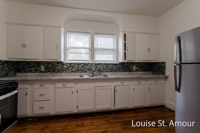 kitchen featuring black electric range, white cabinetry, a sink, and freestanding refrigerator
