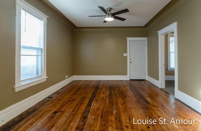 empty room featuring wood-type flooring, visible vents, baseboards, and ceiling fan