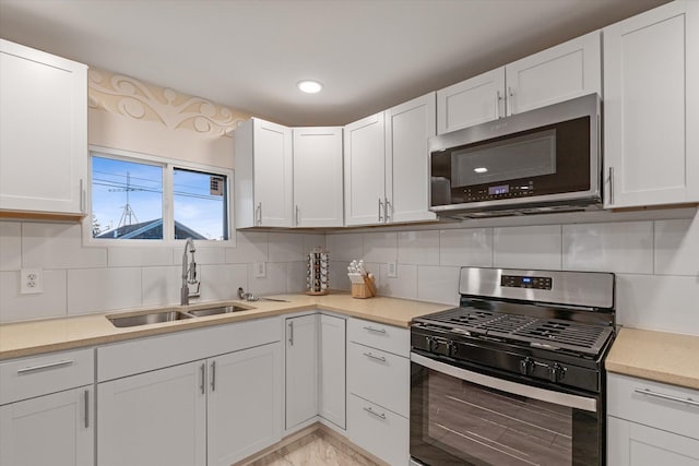 kitchen featuring appliances with stainless steel finishes, decorative backsplash, sink, and white cabinets