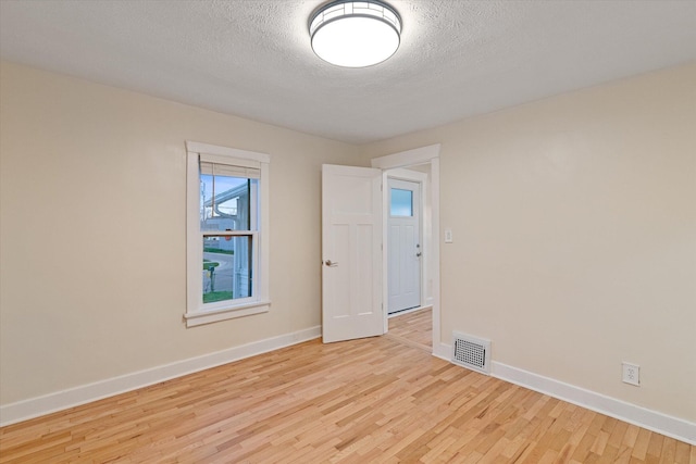 empty room with a textured ceiling and light wood-type flooring