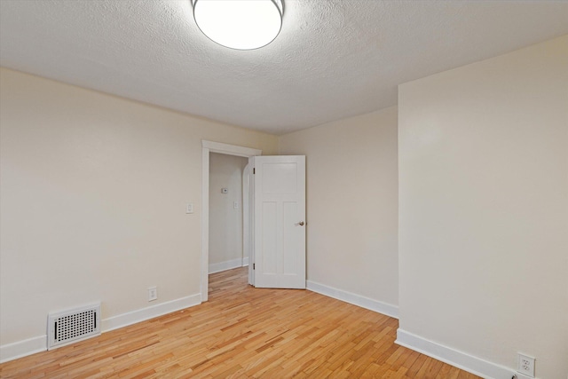 unfurnished room with a textured ceiling and light hardwood / wood-style floors