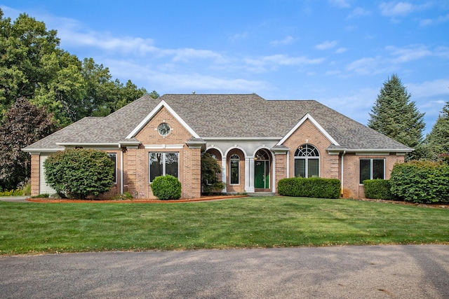 ranch-style house featuring a shingled roof, a front lawn, and brick siding