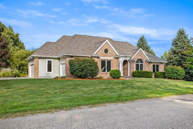 view of front of property featuring an attached garage, a shingled roof, a front lawn, and brick siding