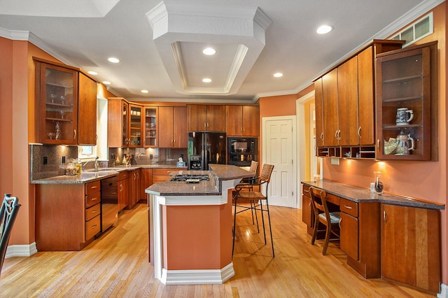 kitchen featuring crown molding, brown cabinetry, black appliances, light wood-type flooring, and a kitchen bar