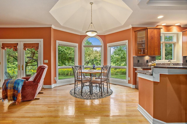 dining room featuring light wood-style floors, french doors, ornamental molding, and baseboards