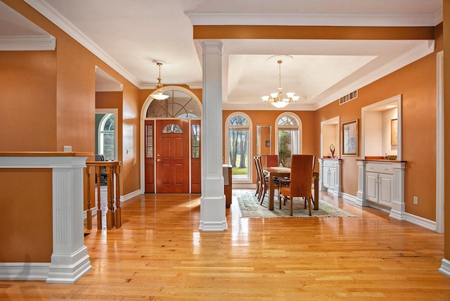 interior space featuring crown molding, decorative columns, a notable chandelier, light wood finished floors, and visible vents