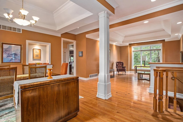 interior space featuring light wood finished floors, a tray ceiling, visible vents, and ornate columns