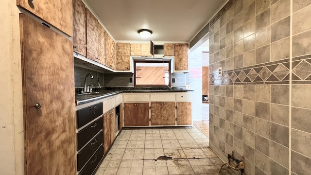 kitchen with wall chimney exhaust hood, tile walls, decorative backsplash, ornamental molding, and sink