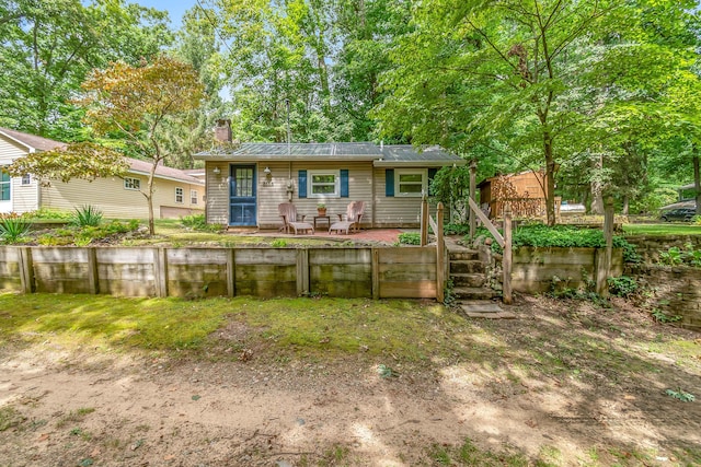 back of property with a deck, metal roof, and a chimney