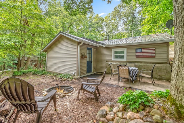 back of house with a fire pit, a patio, and metal roof