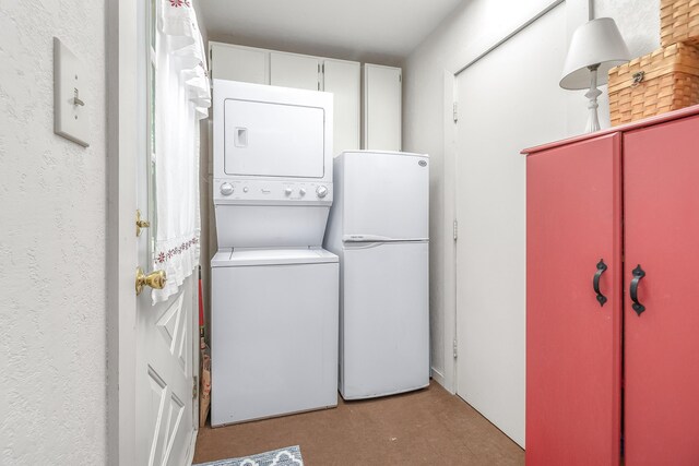 washroom with stacked washer / dryer and cabinets