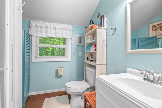 bathroom featuring vaulted ceiling, vanity, toilet, and baseboards