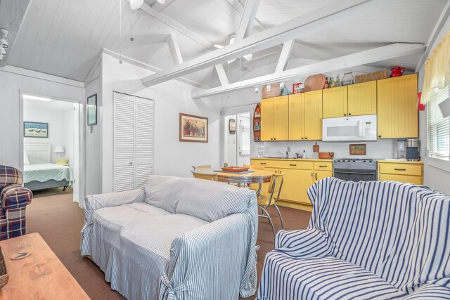 kitchen featuring light brown cabinets, dark carpet, sink, stainless steel range, and vaulted ceiling with beams