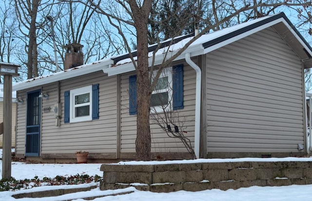 snow covered property featuring a garage and a chimney