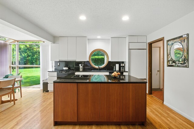 6710 Curtis Rd, Plymouth, MI 48170 - kitchen featuring a kitchen island, white cabinets, modern cabinets, tasteful backsplash, and light wood-style floors