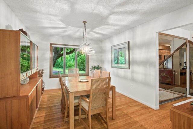 6710 Curtis Rd, Plymouth, MI 48170 - dining room featuring light wood-type flooring, a textured ceiling, and stairs