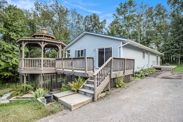 rear view of property featuring a gazebo and a deck