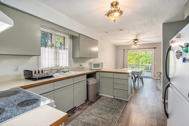 kitchen featuring ceiling fan, dark hardwood / wood-style floors, sink, kitchen peninsula, and white appliances