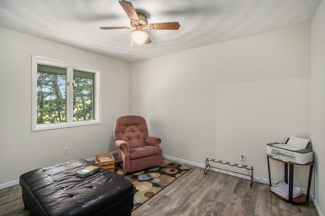 sitting room with ceiling fan and dark wood-type flooring