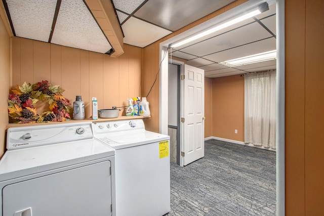 clothes washing area featuring wood walls, dark colored carpet, and separate washer and dryer