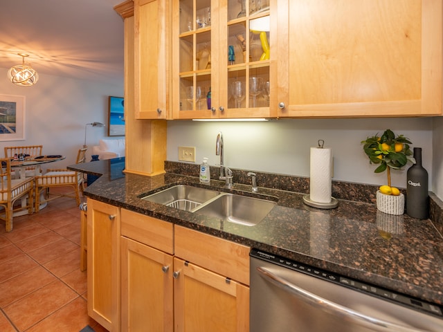 kitchen featuring dark stone countertops, light tile patterned floors, dishwasher, sink, and pendant lighting