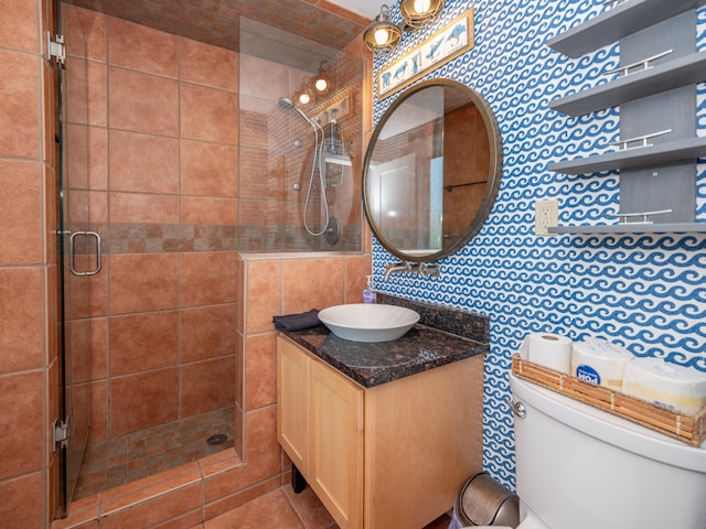 bathroom with vanity, toilet, tile walls, and a shower with door