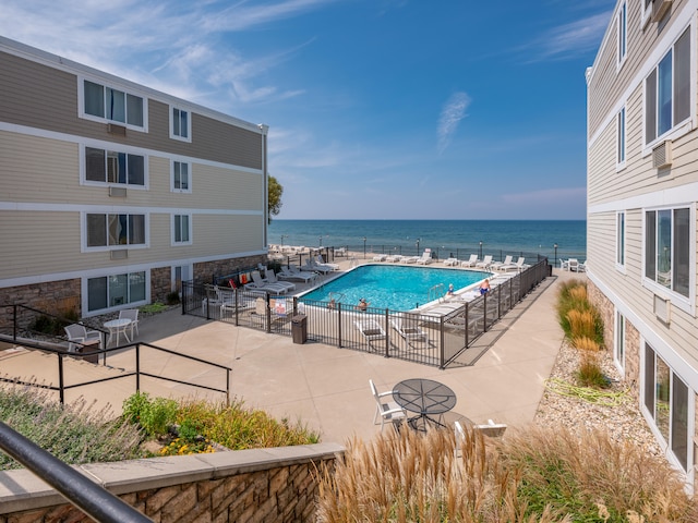 view of pool with a water view and a patio