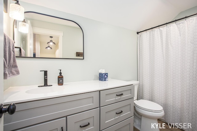 bathroom featuring lofted ceiling, a shower with shower curtain, vanity, and toilet