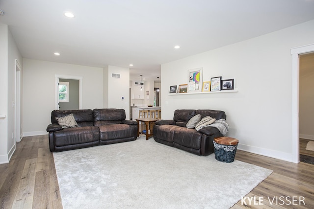 living room with visible vents, baseboards, wood finished floors, and recessed lighting