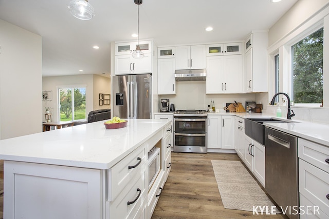 kitchen with stainless steel appliances, recessed lighting, light wood-style flooring, a sink, and a kitchen island