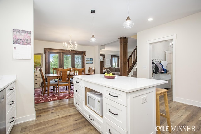 kitchen featuring white microwave, light wood-style flooring, white cabinetry, and a breakfast bar