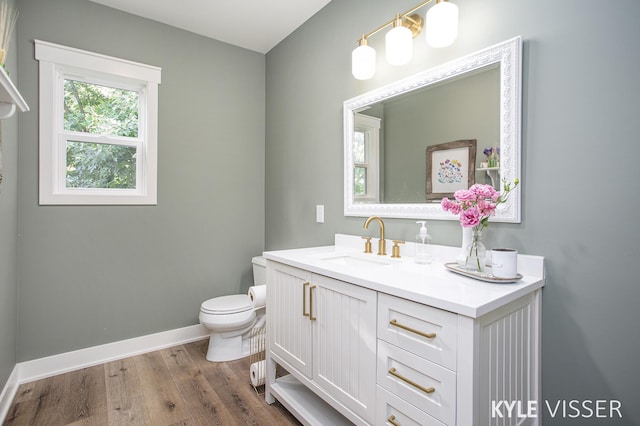 bathroom featuring baseboards, vanity, toilet, and wood finished floors