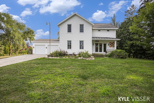 view of front facade with driveway, a garage, metal roof, a standing seam roof, and a front yard