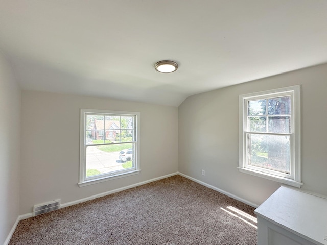 empty room featuring vaulted ceiling and carpet flooring