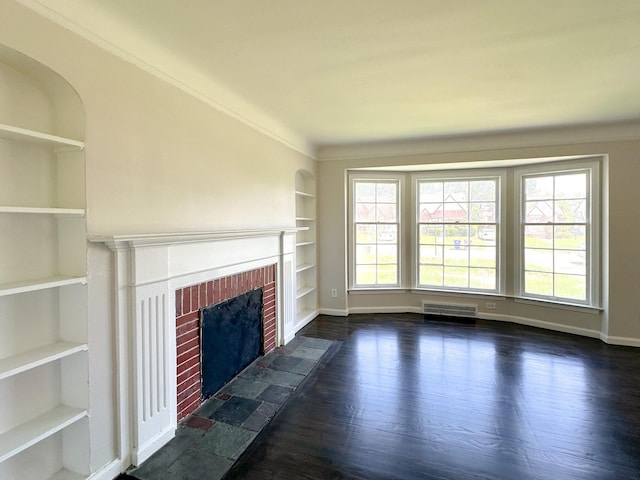 unfurnished living room featuring crown molding, dark hardwood / wood-style flooring, built in features, and a brick fireplace