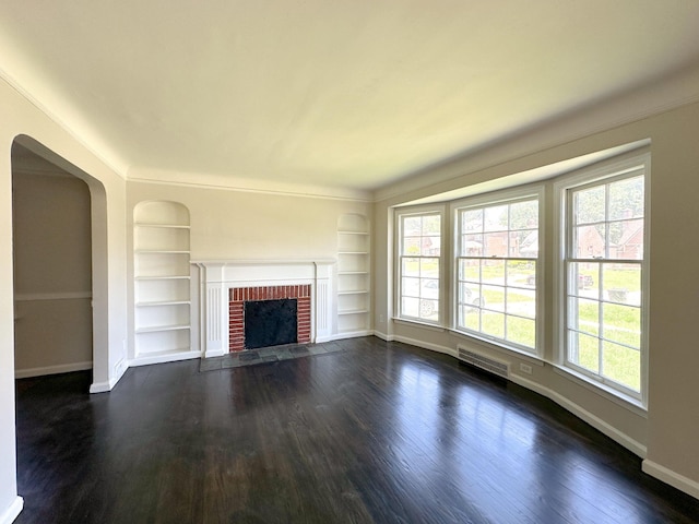 unfurnished living room with a wealth of natural light, dark hardwood / wood-style flooring, and built in shelves