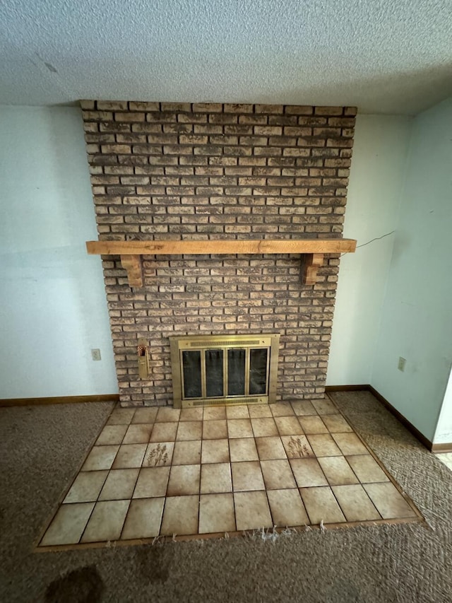 unfurnished living room featuring a brick fireplace, baseboards, carpet floors, and a textured ceiling