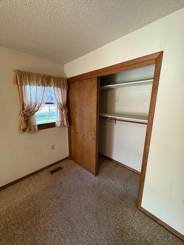 unfurnished bedroom with carpet, baseboards, visible vents, a closet, and a textured ceiling