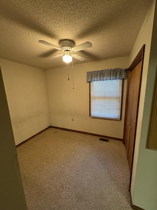 unfurnished bedroom featuring light carpet, visible vents, a ceiling fan, and baseboards