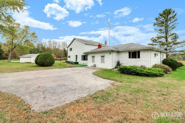 back of house with a lawn and a storage shed