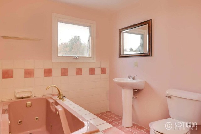 bathroom with a tub to relax in, tile walls, toilet, and tile patterned flooring