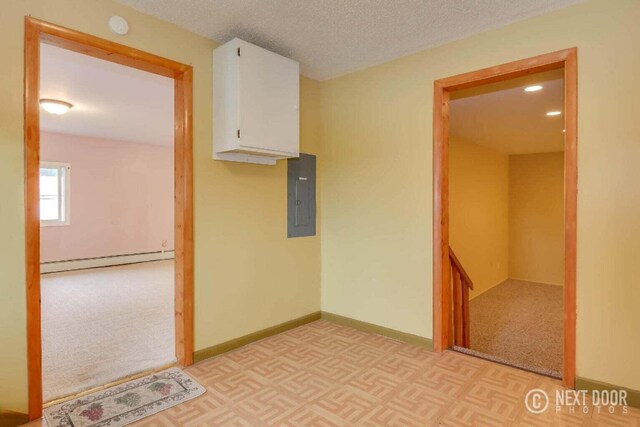 carpeted spare room featuring a baseboard heating unit, electric panel, and a textured ceiling