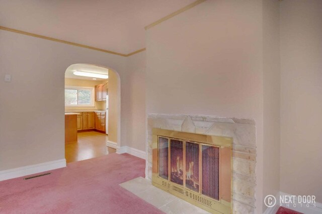 unfurnished living room featuring light carpet, crown molding, and a premium fireplace