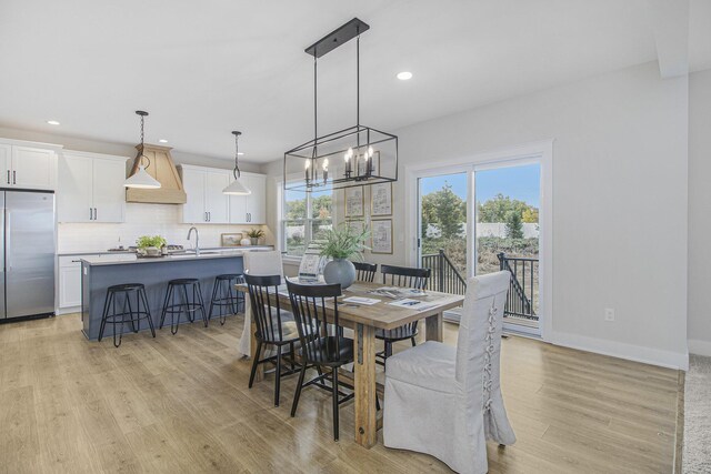 dining area featuring sink, a chandelier, and light hardwood / wood-style flooring